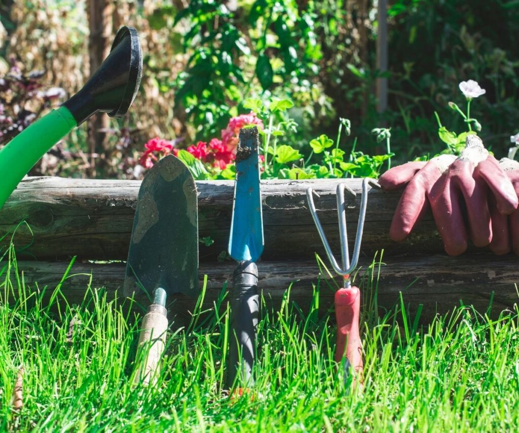gardening hand tools leaning against wooden beam